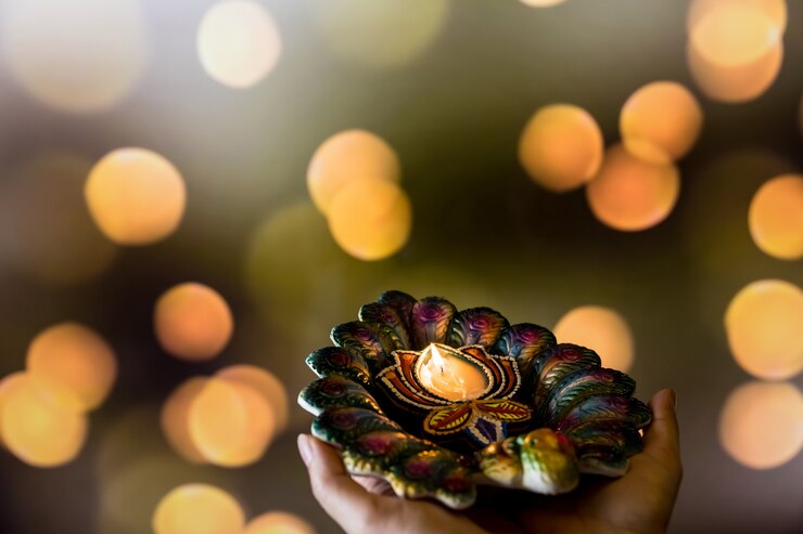 Foto gelukkige diwali - vrouwenhanden met henna die aangestoken kaars houden die op donkere achtergrond wordt geïsoleerd. clay diya-lampen aangestoken tijdens dipavali, hindoe-festival van lichtviering. ruimte voor tekst kopiëren.