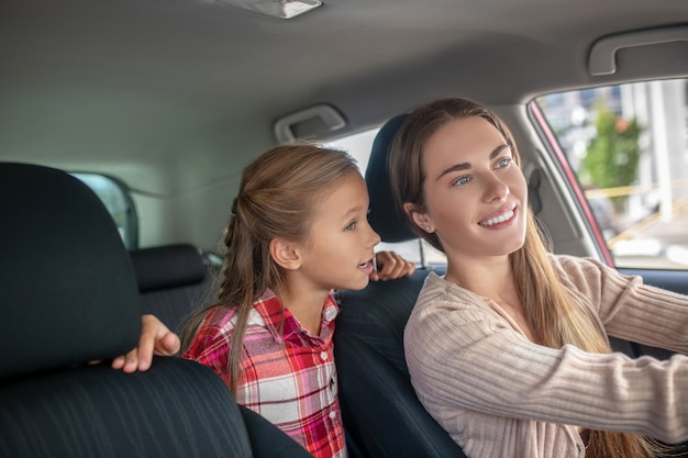 Gelukkige dochter in gesprek met haar moeder vanaf de achterbank van de auto