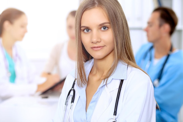 Gelukkige doktersvrouw met medisch personeel in het ziekenhuis dat aan tafel zit en medische geschiedenis bespreekt