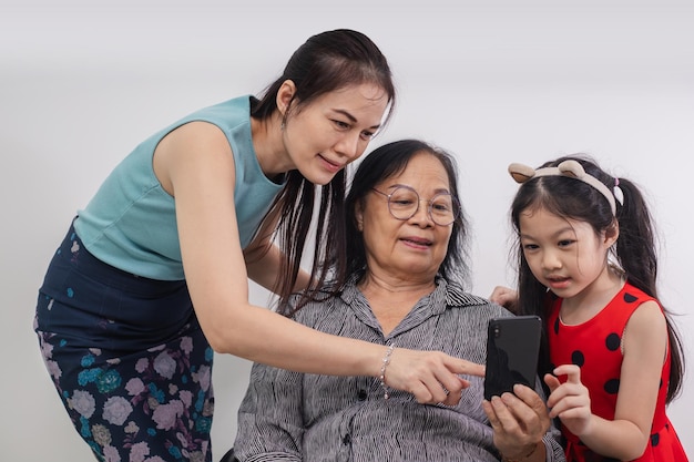 Gelukkige drie generaties vrouwen ontspannen op de bank in de woonkamer met behulp van moderne smartphone