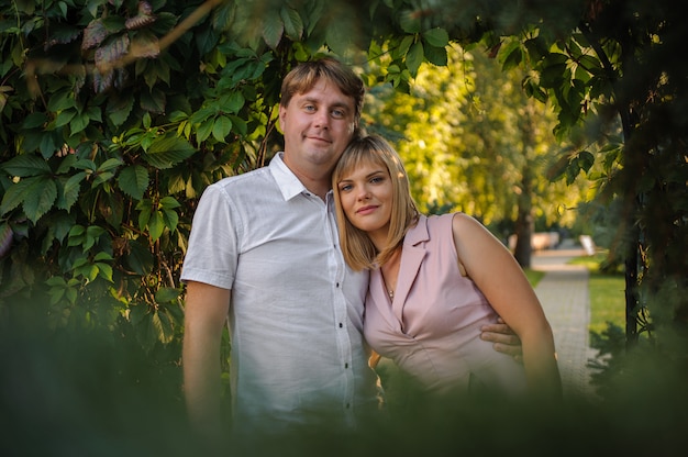 Foto gelukkige echtgenoot en vrouw die in het groene park onder boomtakken koesteren