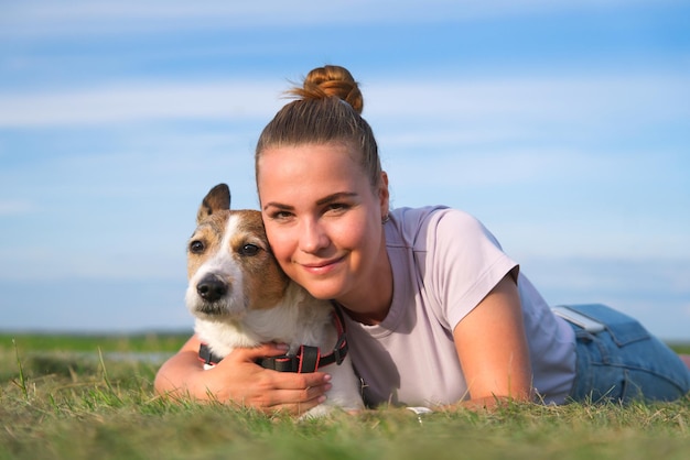 Gelukkige eigenaar jonge vrouw mooi meisje met haar hond liggend op groen gras in park, huisdier knuffelen