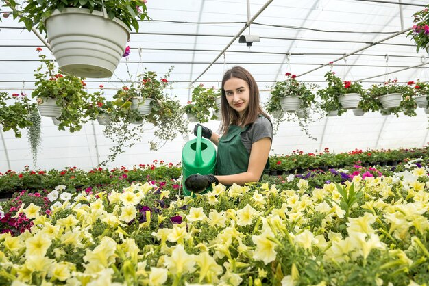 Gelukkige eigenaar van een bloemenboerderij die bloemen water geeft en verzorgt. Dagelijks hard werken voor bloemenproducent in kas