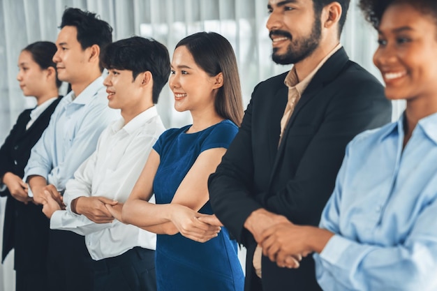 Gelukkige en glimlachende multiraciale kantoormedewerkers houden hand in hand in een rij die synergie en samenwerking voor zakelijk succes bevordert Diverse professionele kantoormedia banden op de moderne werkplek Concord