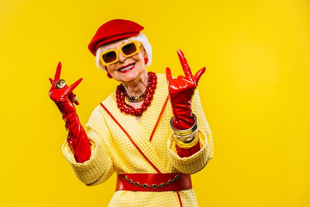 Gelukkige en grappige coole oude dame met modieuze kleding portret op gekleurde achtergrond Jeugdige grootmoeder met extravagante stijlconcepten over levensstijl anciënniteit en ouderen