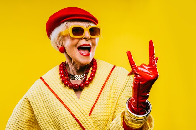 Foto gelukkige en grappige coole oude dame met modieuze kleding portret op gekleurde achtergrond jeugdige grootmoeder met extravagante stijlconcepten over levensstijl anciënniteit en ouderen