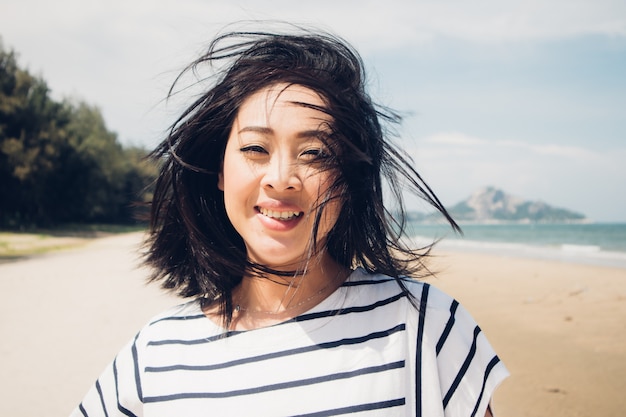 Gelukkige en speelse vrouw die op het strand loopt.