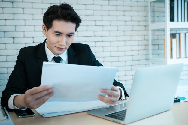 Gelukkige en succesvolle zakenman die aan laptop werkt