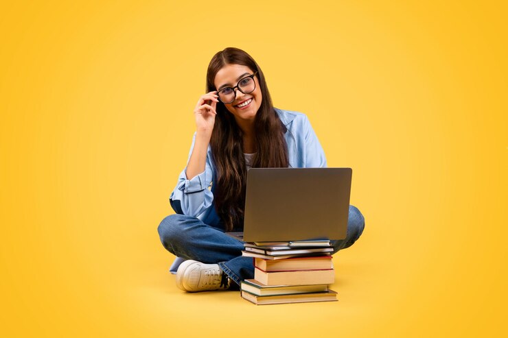 Foto gelukkige europese tiener student vrouw in een bril gebruikt computer met boeken