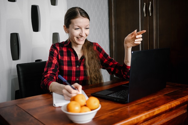 Gelukkige europese vrouwelijke student in casual outfit, glimlachend tijdens het gebruik van laptop