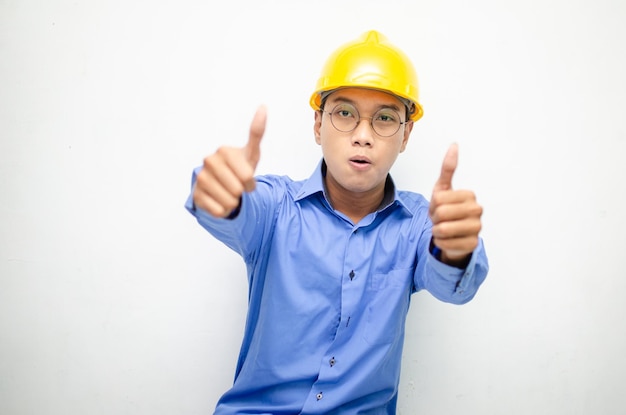 gelukkige extatische aziatische man bouwvakker in blauw shirt met gele veiligheidshelm