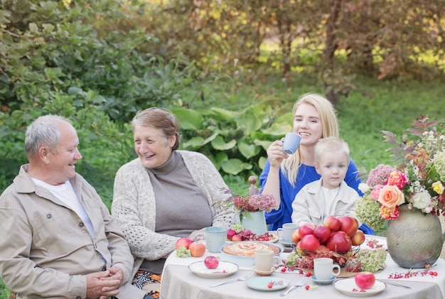Gelukkige familie aan gedekte tafel met appeltaart in de tuin