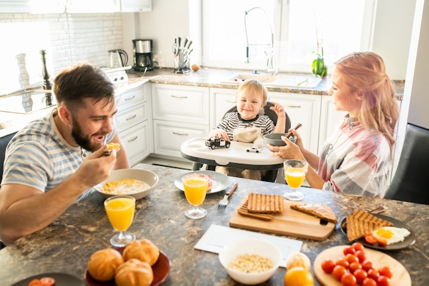 Foto gelukkige familie aan keukentafel in de ochtend