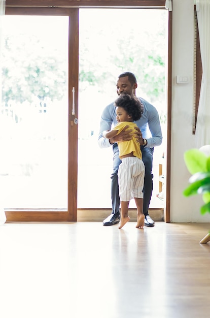 Gelukkige familie Afro-Amerikaanse zoon rent en knuffelt vader nadat hij terug is van kantoor Welkom terug thuis papa en Sweet Moments of Fatherhood concept