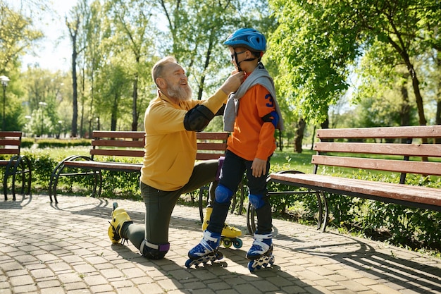 Gelukkige familie bereidt zich voor op extreem rolschaatsen in het stadspark in het weekend. Papa zet een beschermende helm op het hoofd van zijn zoon