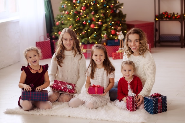 Gelukkige familie bij de kerstboom thuis met geschenken