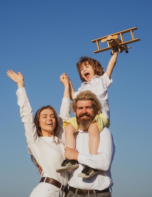 Gelukkige familie buiten ouders met kind jongen met speelgoed vliegtuig op vaders schouders moederschap vader