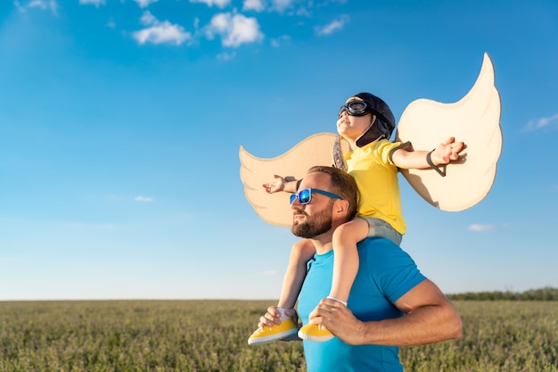 Gelukkige familie buiten plezier. Vader en zoon spelen tegen blauwe zomer hemelachtergrond.