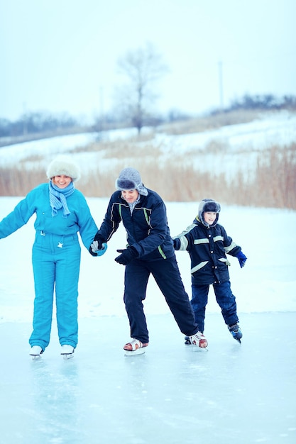 Gelukkige familie buiten schaatsen op ijsbaan.
