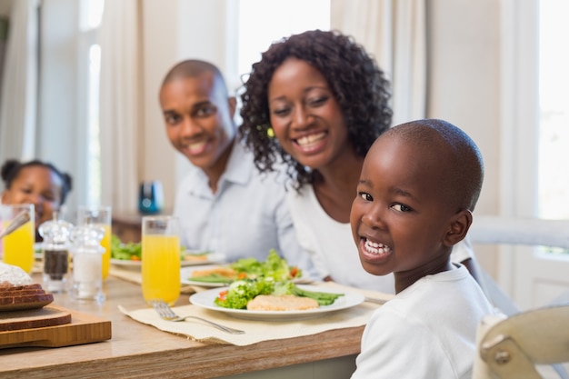 Gelukkige familie die bij camera bij lunch glimlacht