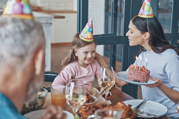 Gelukkige familie die de verjaardag van een klein meisje viert terwijl ze thuis aan de eettafel zit