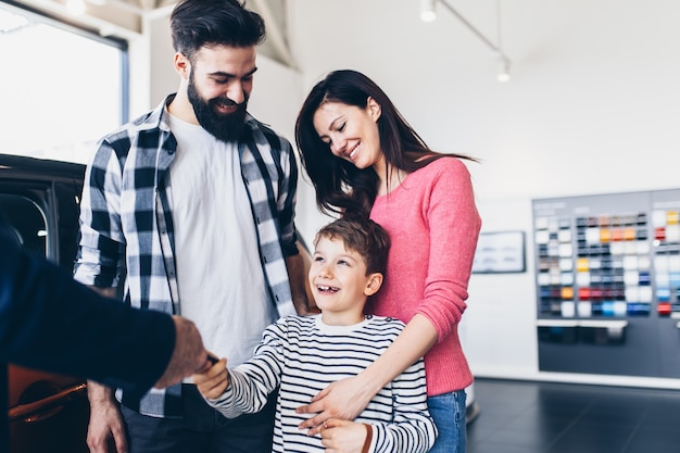 Gelukkige familie die een nieuwe auto koopt bij de autoshowroom