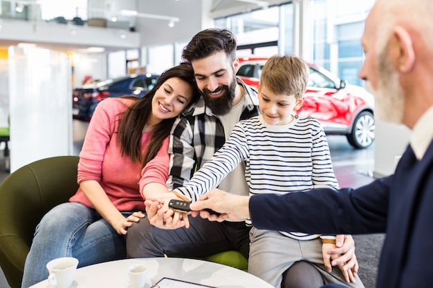 Gelukkige familie die een nieuwe auto koopt bij de autoshowroom.