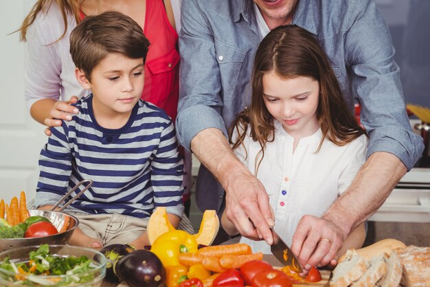 Gelukkige familie die een plantaardige salade voorbereidt