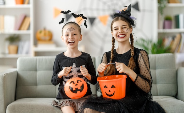 Gelukkige familie die Halloween viert Leuke kinderen in carnavalskostuums met schilderij pompoenen thuis