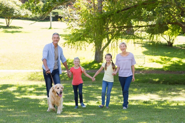 Gelukkige familie die in het park met hun hond loopt