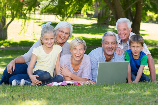 Gelukkige familie die laptop in het park met behulp van