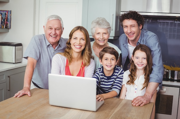 Gelukkige familie die laptop in keuken met behulp van