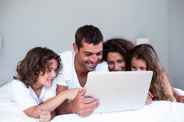 Gelukkige familie die laptop samen op bed met behulp van