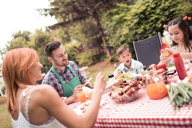 Gelukkige familie die lunch in de tuin heeft