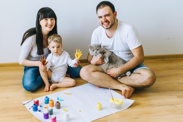 Gelukkige familie die op papier bij parketvloer met een kat schetsen