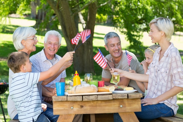 Gelukkige familie die picknick heeft en Amerikaanse vlag houdt