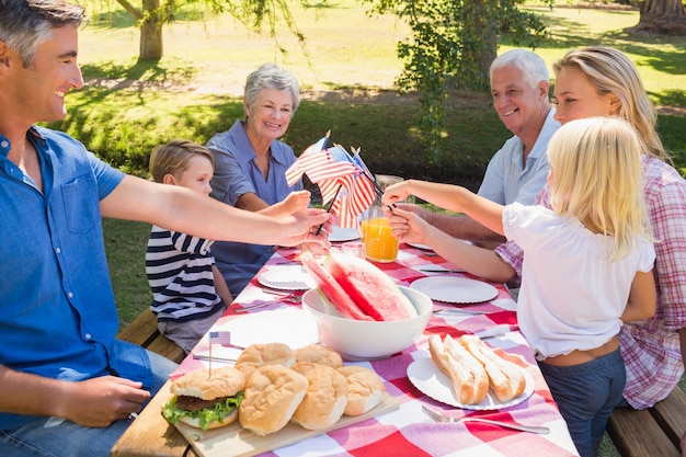 Gelukkige familie die picknick heeft en Amerikaanse vlag houdt