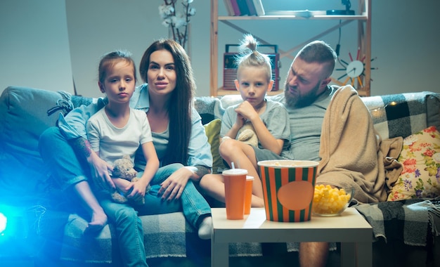 Gelukkige familie die 's avonds thuis naar projector-tv-films met popcorn kijkt