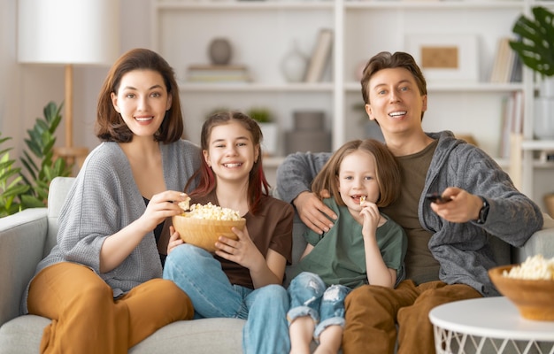 Gelukkige familie die 's avonds thuis naar projector-tv-films met popcorn kijkt