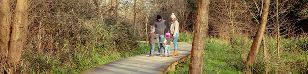 Gelukkige familie die samen praat en speelt over een houten pad naar het bos