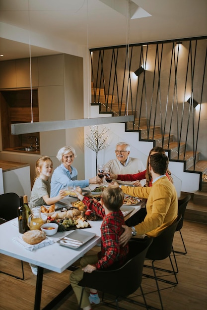 Gelukkige familie die thuis een diner met rode wijn heeft