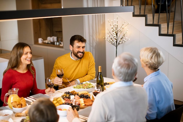 Gelukkige familie die thuis een diner met rode wijn heeft