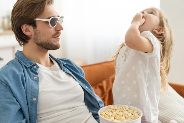 Gelukkige familie die thuis tv kijkt en popcorn eet.