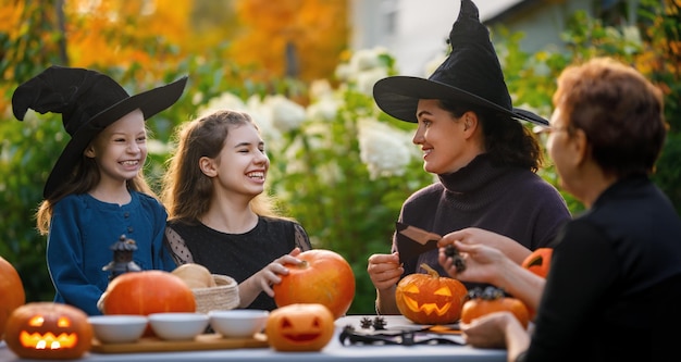 Gelukkige familie die zich voorbereidt op Halloween Moeder grootmoeder en kinderen die pompoenen snijden