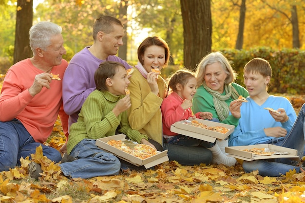 Gelukkige familie eet samen pizza in het herfstpark