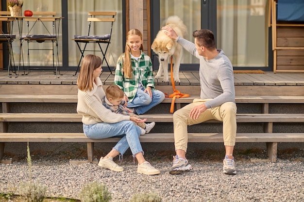 Foto gelukkige familie en hond zittend op de veranda van het huis communiceren