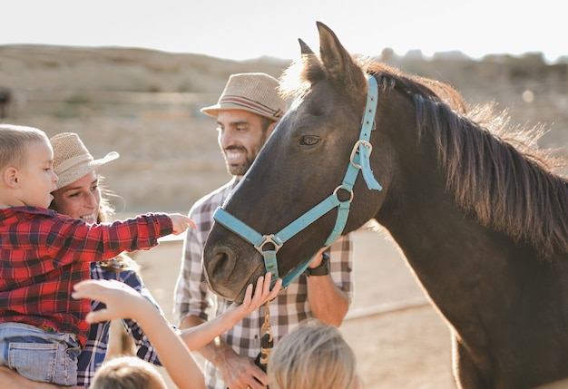 Gelukkige familie geniet van een dag buiten op de paardenranch - Ouders en kinderen met paard - Dierenliefde