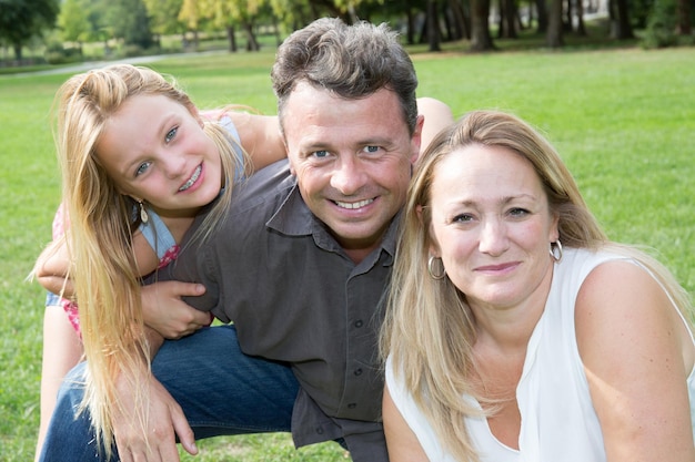 Foto gelukkige familie genieten van de zon in een park glimlachend in de camera