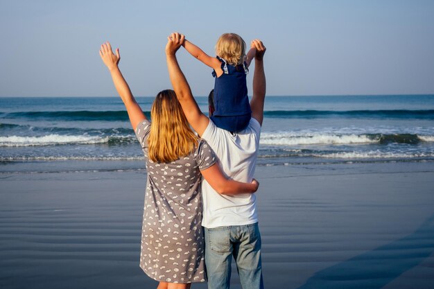 Gelukkige familie hand in hand op het strand en kijken naar de zonsondergang op de oceaan van Goa India