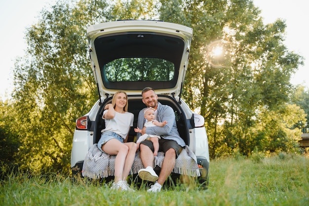 Gelukkige familie in de buurt van auto kofferbak op zonnige dag. Rondrit